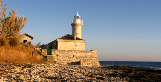 An old stone-built lighthouse - the original beautiful white colour shines gold in the evening light.